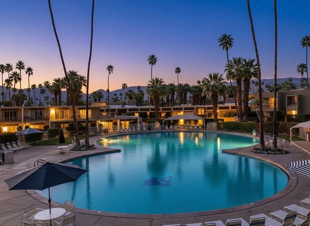 Resort pool at twilight framed by palms and mountains