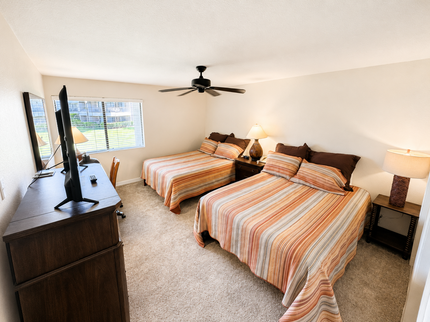 Guest bedroom with two queen beds, ceiling fan, and greenbelt window